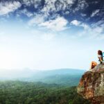 I'd give anything to be this healthy. A woman sat on a cliff looking at the scenery below.